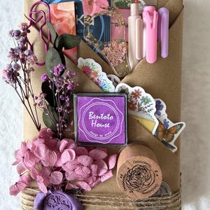 May include: A brown paper package tied with twine, adorned with dried flowers, stickers, and stationery. Includes a purple ink pad with the text "Bentoto House", a wooden stamp, and a purple wax seal.