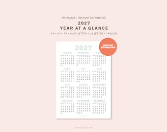 May include: A printable 2027 year at a glance calendar featuring twelve months from January to December. The document includes text labels for A5, A4, A3, half letter, US letter, and tabloid sizes, with a circular orange instant download badge.