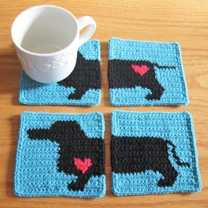 May include: Four crocheted coasters featuring a black silhouette of a dachshund with a red heart on its back. The coasters are turquoise blue with a black border.
