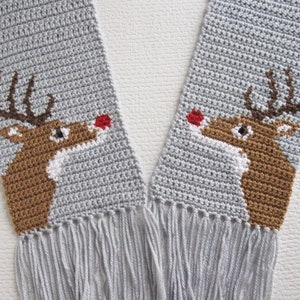 May include: A gray crocheted scarf with two brown reindeer faces, each with a red nose, and gray fringe on the ends.