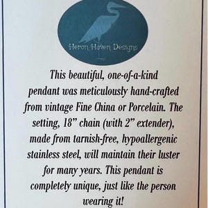 May include: A white card with text describing a handcrafted pendant from Heron Haven Designs. The pendant is made from vintage Fine China or Porcelain, with an 18-inch chain and a 2-inch extender.