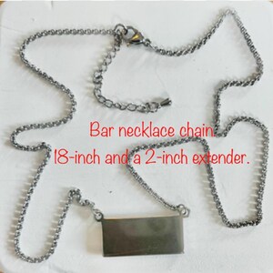 May include: Silver-toned bar necklace with an 18-inch chain and a 2-inch extender. The rectangular bar pendant hangs from a delicate chain. The text "Bar necklace chain 18-inch and a 2-inch extender" is visible.