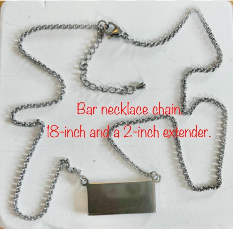 May include: Silver-toned bar necklace with an 18-inch chain and a 2-inch extender. The rectangular bar pendant hangs from a delicate chain. The text "Bar necklace chain 18-inch and a 2-inch extender" is visible.