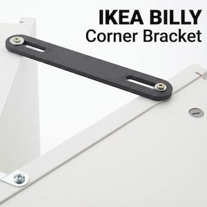 May include: A black IKEA BILLY Corner Bracket is shown, attached to white furniture. The bracket is a long, rectangular piece with two holes for screws. The text "IKEA BILLY Corner Bracket" is displayed in black.