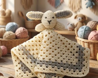 Può includere: Un doudou all'uncinetto color crema con una testa di coniglio dalle orecchie lunghe e un corpo a copertina granny square. La copertina ha un centro color crema con un bordo grigio. La testa del coniglio presenta tratti del viso ricamati in marrone.