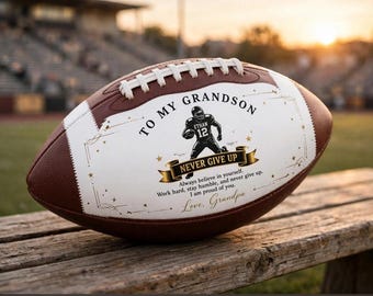 Può includere: Un pallone da football americano marrone e bianco con la grafica stampata di un giocatore con il numero 12. Il testo recita: TO MY GRANDSON, NEVER GIVE UP, Always believe in yourself. Work hard, stay humble, and never give up. I am proud of you. Love, Grandpa.