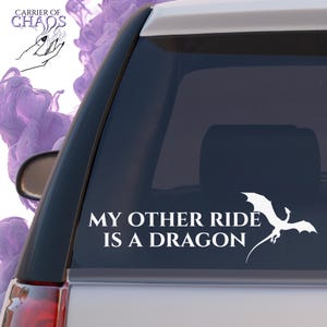 May include: White vinyl decal for a car window featuring a dragon silhouette and the text "MY OTHER RIDE IS A DRAGON". The decal is applied to the rear window of a vehicle.