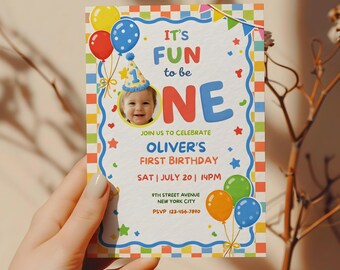 Puede incluir: Una colorida invitación de cumpleaños con el texto "It's Fun to be One". La invitación presenta una foto de un bebé con un gorro de fiesta, globos y estrellas. La invitación es para el primer cumpleaños de Oliver.