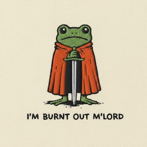Puede incluir: Diseño bordado de una rana verde con una capa naranja y una espada. El texto "I'M BURNT OUT M'LORD" está debajo. El diseño está sobre un fondo crema. Diseño humorístico y de fantasía.