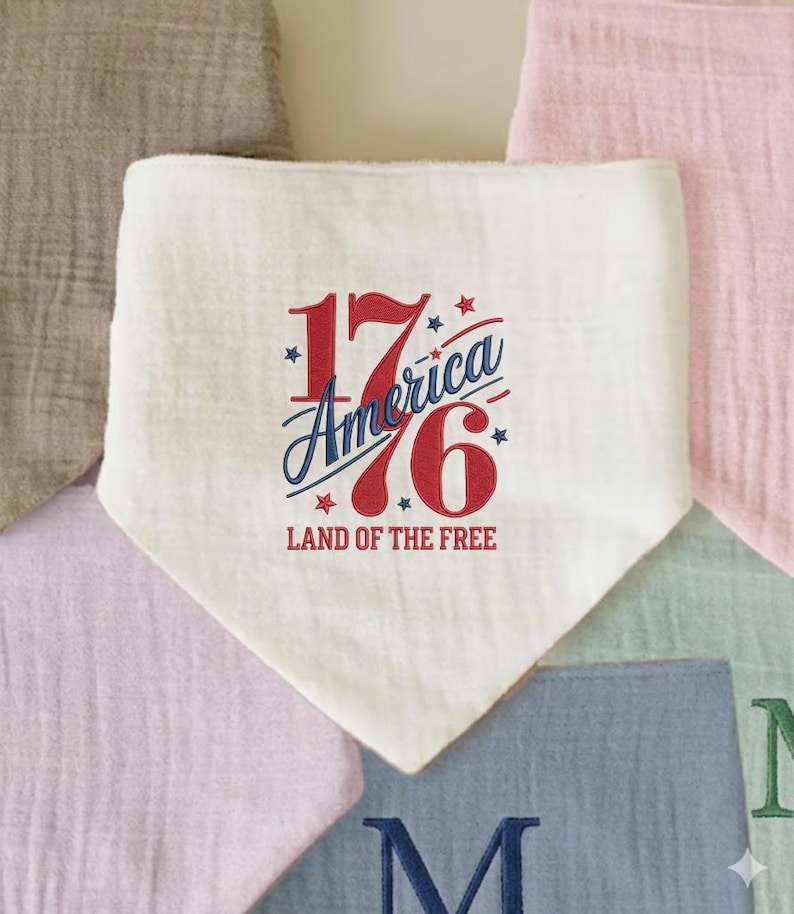 K&ouml;nnte beinhalten: Ein wei&szlig;es L&auml;tzchen im Bandana-Stil mit dem Text "1776 America Land of the Free" in Rot und Blau. Das L&auml;tzchen ist von anderen pastellfarbenen Stoffquadraten umgeben.