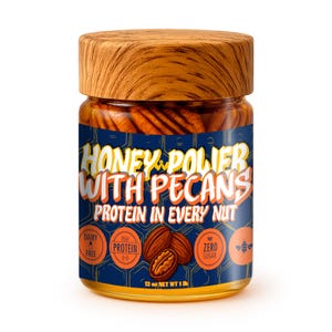 Könnte beinhalten: Ein Glas mit Honig und Pekannüssen, bedeckt mit einem Holzdeckel. Das Glas hat ein blaues Etikett mit der Aufschrift "HONEY & POWER WITH PECANS" und "PROTEIN IN EVERY NUT". Das Etikett enthält auch Symbole für milchfrei, hoher Proteingehalt und ohne Zucker. Das Glas enthält 340 Gramm.