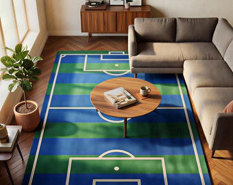 May include: A blue and green striped rug designed as a football pitch. White lines define the field's layout. A round wooden coffee table rests on the rug. The room includes a grey sofa and a wooden cabinet with framed pictures.