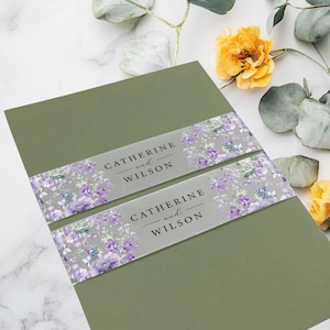 May include: Olive green wedding invitation with a floral band featuring the names "Catherine and Wilson" in black text. The floral band has purple and gray flowers. The invitation is decorated with yellow flowers and green leaves.