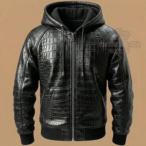 Könnte beinhalten: Schwarze Lederjacke mit Kapuze und Krokodilhautstruktur. Die Jacke hat einen durchgehenden Reißverschluss, eine Kapuze mit schwarzem Futter sowie einen gerippten Saum und Bündchen. Sie hat zwei Vordertaschen und einen Kordelzug an der Kapuze.