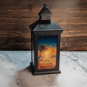 May include: Black lantern with a beach scene and the text "It's 5 o'clock somewhere!" printed on the front.