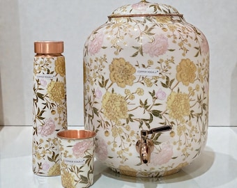 Könnte beinhalten: Ein Set aus kupferfarbenen Trinkgefäßen mit floralem Muster. Das Set umfasst einen Wasserspender, eine Flasche und einen Becher. Der Spender hat einen Wasserhahn und einen Deckel. Auf Flasche und Becher steht "COPPER YOGA".