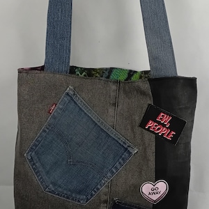 May include: A patchwork denim tote bag with blue denim straps. The bag features a Levi's pocket, patches with text like "EW, PEOPLE" and "GO AWAY", and a "SOCIALY AWKWARD" patch.