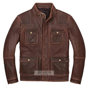 Könnte beinhalten: Braune Lederjacke mit Stehkragen, vier Vordertaschen und Schulterpatches. Die Jacke hat ein Used-Finish und eine Schnalle am Kragen. Der Markenname "AVARON JACKETS" ist unten rechts sichtbar.