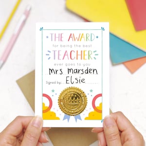 May include: A colorful card with a gold seal that reads "Official Document to prove that" with a crown on top. The card says "The Award for being the best Teacher ever goes to you Mrs Marsden Signed by: Elsie"