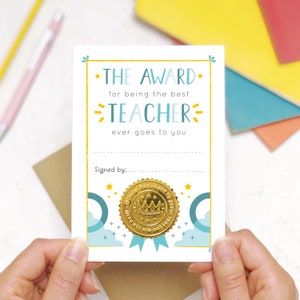 May include: A white card with a gold seal and the text "THE AWARD for being the best TEACHER ever goes to you" and "Signed by:"