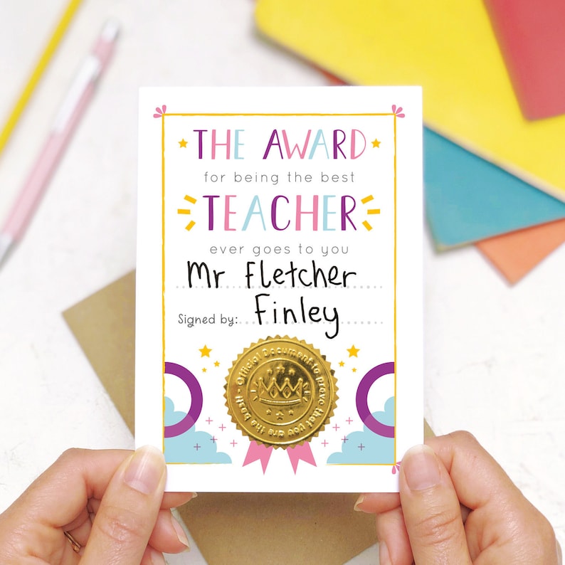 May include: A pink and blue card with a gold seal that reads "Official Document to Prove That You Are The Best Teacher Ever". The card says "The Award for being the best Teacher ever goes to you Mr Fletcher... Signed by: Finley".