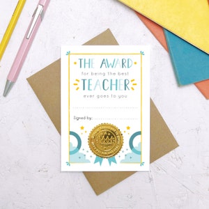 May include: A light blue and white card with a gold foil seal. The card reads "The Award for being the best Teacher ever goes to you."  The card has a space for a signature and a gold foil seal with a crown and the words "Official  Acknowledgement to make you feel good about you".