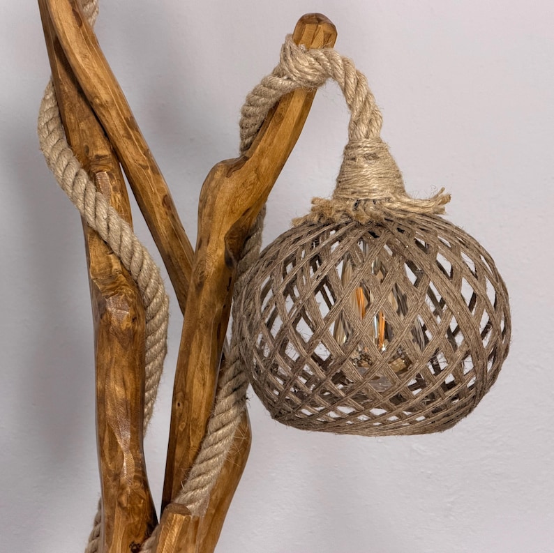 Peut inclure: Lampe de sol rustique en bois avec abat-jour en ficelle tress&eacute;e. La lampe pr&eacute;sente une base en bois naturel avec des accents de corde et un abat-jour sph&eacute;rique. L'ampoule est visible &agrave; l'int&eacute;rieur de l'abat-jour. La lampe est con&ccedil;ue pour une utilisation en int&eacute;rieur.