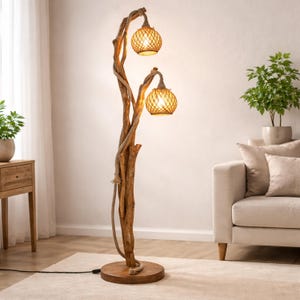 Peut inclure: Un lampadaire en bois avec un design naturel en forme d'arbre. La lampe comporte deux abat-jours globes tiss&eacute;s et est enroul&eacute;e de corde. La base est une plateforme en bois ronde. La lampe est branch&eacute;e sur une prise murale.