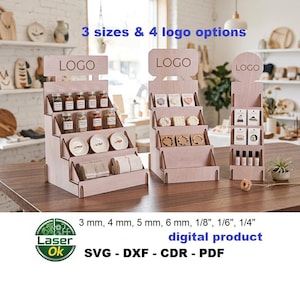 Op de afbeelding: Drie lichtgekleurde houten displays met treden en lasergesneden sleuven voor producten. Elke display heeft een bovenpaneel met het woord LOGO. De tekst 3 mm, 4 mm, 5 mm, 6 mm, 1/8", 1/6", 1/4" en digital product SVG - DXF - CDR - PDF is zichtbaar.