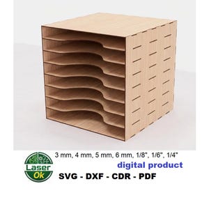 Può includere: Un organizer in legno chiaro tagliato al laser con otto ripiani curvi. L'organizer a forma di cubo ha fessure verticali sui lati. L'immagine include il testo "digital product" e "SVG - DXF - CDR - PDF".