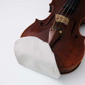 May include: A close-up of a brown violin with a white shoulder rest. The violin has a wooden body, black strings, and a bridge. The shoulder rest is made of a soft, white material and is designed to provide comfort while playing.