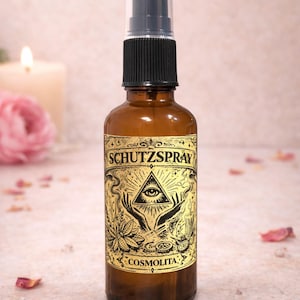 Könnte beinhalten: Eine braune Glassprühflasche mit schwarzem Kunststoffaufsatz. Das goldene Etikett mit schwarzer Schrift zeigt eine Illustration eines Auges in einem Dreieck über zwei Händen sowie den aufgedruckten Text SCHUTZSPRAY und COSMOLITA.