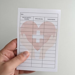 May include: A white medical chart featuring a heart and cross design. The chart includes sections for patient details, such as date, name, and comments. The chart is held in a hand.