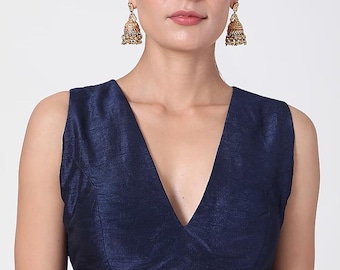 Peut inclure: Un chemisier sans manches bleu marine avec un col en V profond. Le chemisier a un éclat subtil et une coupe ajustée. Le modèle porte des boucles d'oreilles dorées ornées. Le chemisier est une pièce classique et polyvalente.