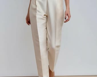 Pantalón ancho de satén color crema, cintura alta y bolsillos, para uso informal.