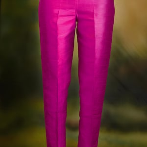 May include: Bright fuchsia-colored pants with a tailored fit. The pants have a smooth, silky texture and a classic design. The image shows the pants from the waist down, highlighting the sleek silhouette and vibrant color. The pants are part of a fashion collection.