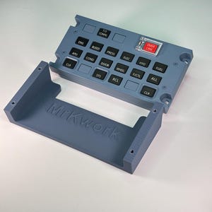 Könnte beinhalten: Ein graues, 3D-gedrucktes Flugzeug-Bedienfeld mit schwarzen Tasten, beschriftet mit ENG, BLEED, PRESS, ELEC, HYD, FUEL, APU, COND, DOOR, WHEEL, F/CTL, ALL, STS, RCL, CLR und T.O CONFIG. Ein roter EMER CANC-Knopf hat eine transparente Abdeckung. MrKwork steht auf der Basis.