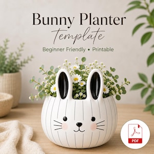 Può includere: Un vaso a forma di coniglio in ceramica bianca con strisce verticali nere, orecchie nere e un volto stampato con guance rosa. Il testo recita Bunny Planter Template, Beginner Friendly, Printable. Un'icona PDF rossa è visibile in basso a destra.