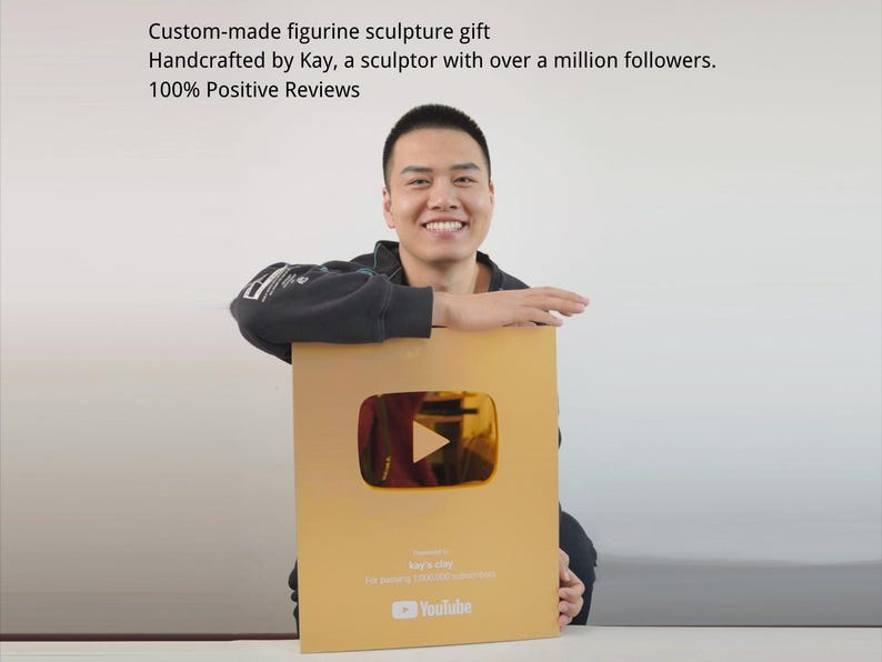 以下が含まれることがあります： 大きな金色のYouTube再生ボタンアワードを持つ人物。アワードには再生ボタンのシンボルとYouTubeのロゴがあります。アワードのテキストには「Kay's Play」と「100％ポジティブレビュー」と書かれています。