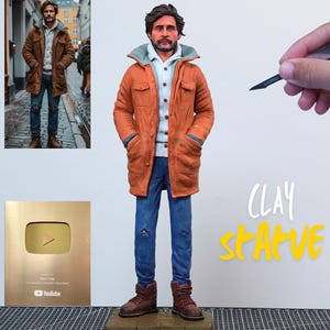 May include: A clay sculpture of a person wearing a brown jacket, blue jeans, and brown boots. The sculpture is standing on a small platform. A gold-colored YouTube play button is on the left. The words "CLAY STATUE" are written in yellow.
