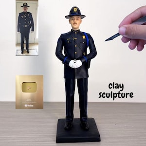 以下が含まれることがあります： 濃紺の制服、帽子、手袋を着用した警察官の粘土彫刻。彫刻は黒い台座に立っています。画像には、金のプラークと警察の制服を着た人の写真も含まれています。「clay sculpture」という文字が表示されています。