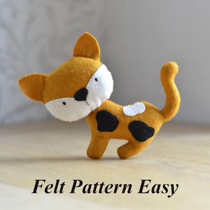 May include: A handmade felt cat toy in shades of yellow, white, and black. The cat has a white face, black eye patch, and black spots on its body. The text "Felt Pattern Easy" is at the bottom.