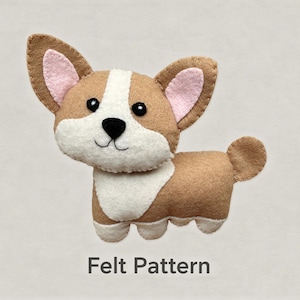 Könnte beinhalten: Ein Corgi-Hundeornament aus Filz in Beige und Weiß mit rosa Innenohren, schwarzen Perlenaugen sowie einer gestickten schwarzen Nase und einem Mund. Der Hund hat eine weiße Brust und ein weißes Gesicht. Der Text Felt Pattern steht unter dem Hund.