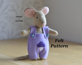 May include: A tan felt mouse doll wearing purple overalls with a dark purple mushroom applique on the front. The mouse has large pink-lined ears and a small pink nose. The text mouse + overalls and Felt Pattern is visible in the image.