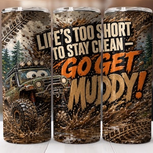 Könnte beinhalten: Ein zylindrischer Becher mit einer Grafik eines Geländewagens, der durch Schlamm fährt. Das Design enthält den Text "LIFE'S TOO SHORT TO STAY CLEAN - GO GET MUDDY!" in fetter Schrift vor einem Hintergrund aus Wald und Reifenspuren.