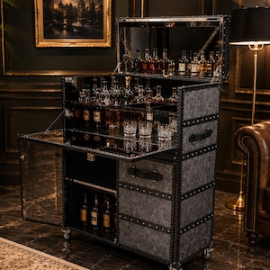 Può includere: Un mobile bar grigio in stile vintage con più ripiani e uno schienale a specchio. L'armadio è pieno di varie bottiglie di liquore e vetreria. Ha un coperchio incernierato e una porta a ribalta, ed è su ruote.