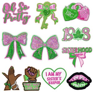 May include: A collection of embroidered patches in shades of pink and green. Designs include bows, hearts, lips, a key, and text that reads "Oh So Pretty", "Big", "Sisterhood", "I Am My Sister's Keeper", and "They Not Like Us".
