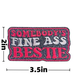 May include: Embroidered patch with the text "SOMEBODY'S FINE ASS BESTIE" in white and pink lettering. The patch is rectangular, measuring 3.5 inches wide and 2 inches high, with a glittery dark blue border.