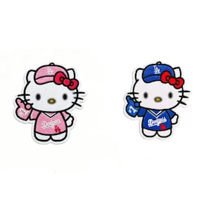 May include: Two embroidered patches featuring a cartoon cat wearing a baseball uniform. One patch is pink with a pink cap and the other is blue with a blue cap. Both patches have the word "Dodgers" on the jersey.