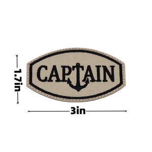 May include: A beige embroidered patch with the word "CAPTAIN" in black, featuring an anchor design. The patch is 3 inches wide and 1.7 inches high, with a black border.